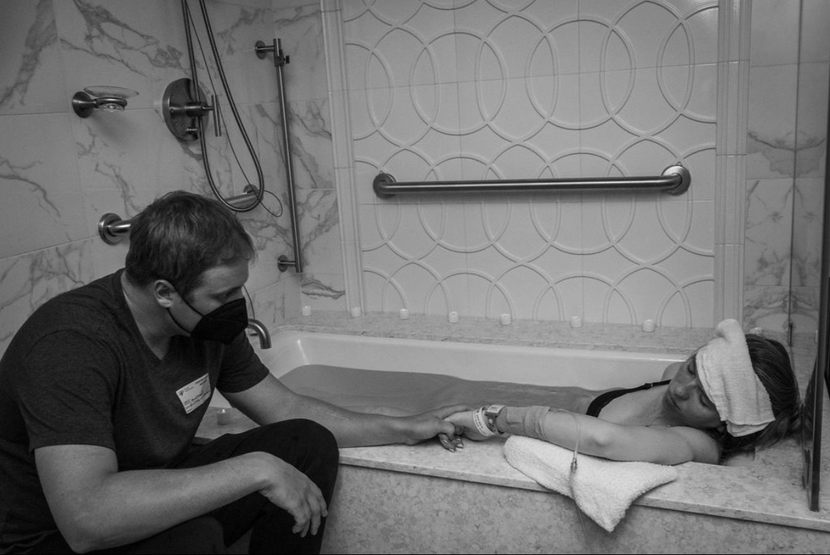 Maddy's husband Tony holding her hand in the birth tub during one of her hospital labors